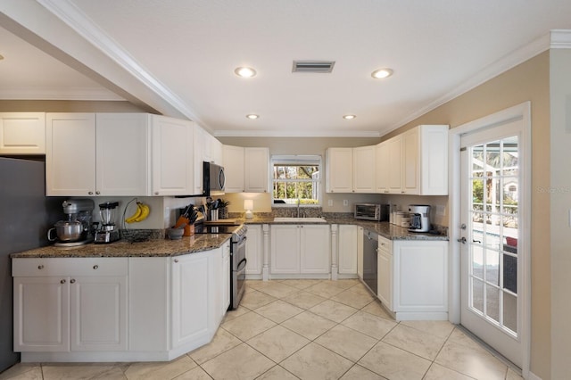 kitchen with white cabinetry, crown molding, appliances with stainless steel finishes, and dark stone counters