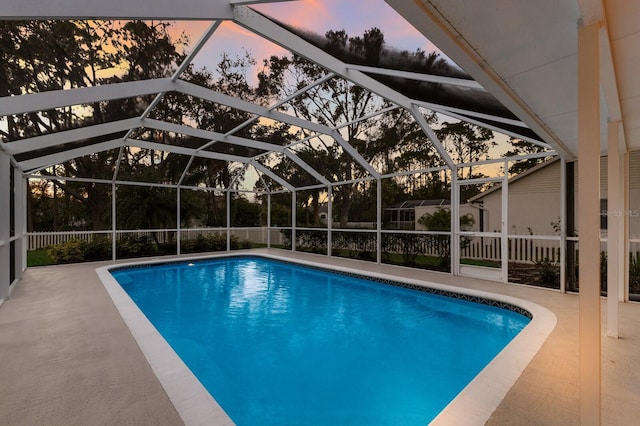 pool at dusk with a patio area and a lanai