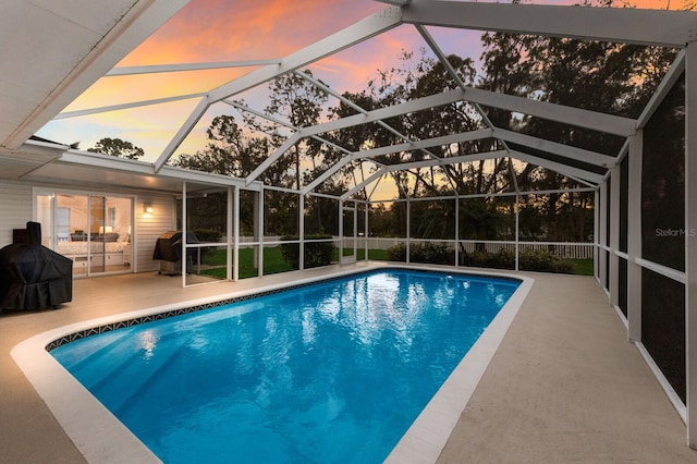 pool at dusk featuring a patio area and a lanai