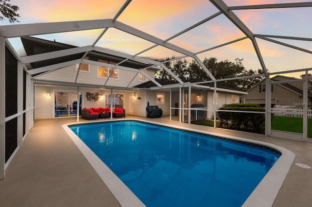 pool at dusk featuring a patio and glass enclosure