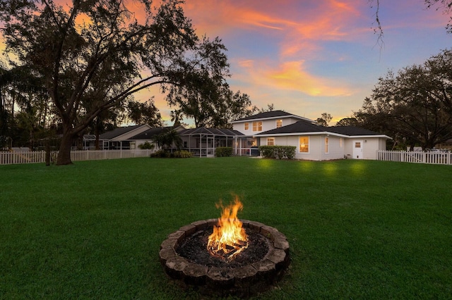 yard at dusk featuring a fire pit and glass enclosure