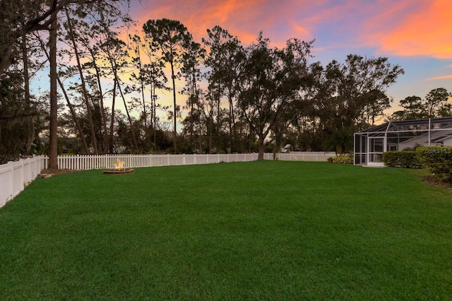 yard at dusk featuring glass enclosure