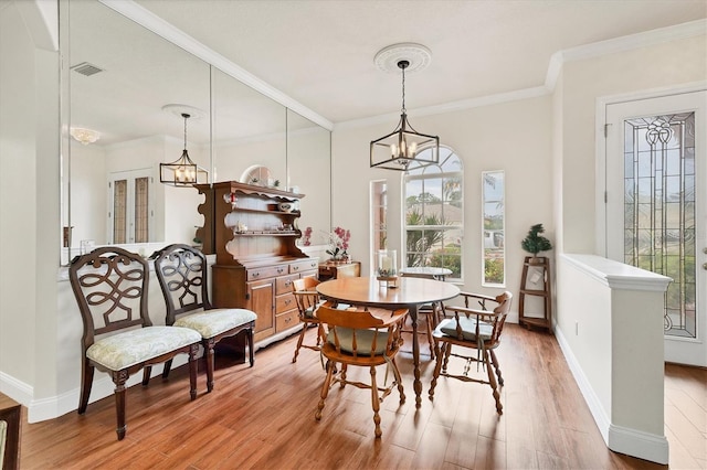 dining space with a chandelier, light hardwood / wood-style flooring, and crown molding