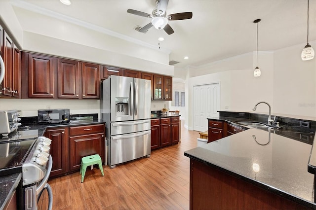 kitchen with ceiling fan, appliances with stainless steel finishes, light hardwood / wood-style flooring, sink, and decorative light fixtures