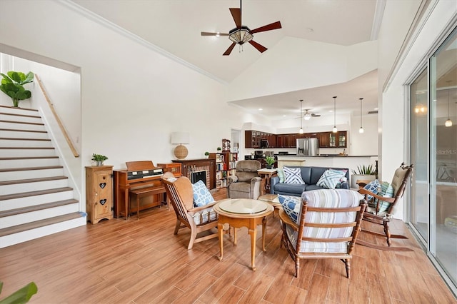 7341 Featherstone Blvd, Sarasota, FL 34238 - living room with a ceiling fan, light wood-style flooring, stairway, high vaulted ceiling, and crown molding