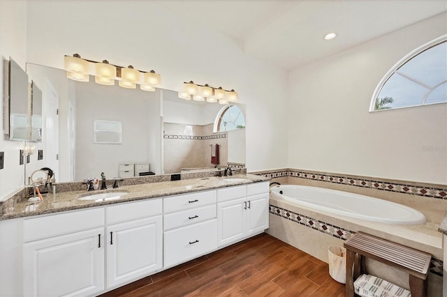 bathroom with vanity, hardwood / wood-style flooring, and tiled tub