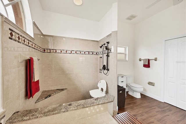 bathroom featuring toilet, hardwood / wood-style flooring, and tiled shower