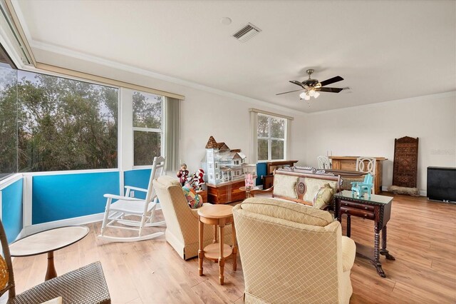 living room with light hardwood / wood-style floors, crown molding, a healthy amount of sunlight, and ceiling fan