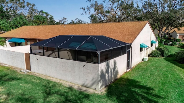 back of property featuring a lanai and a lawn