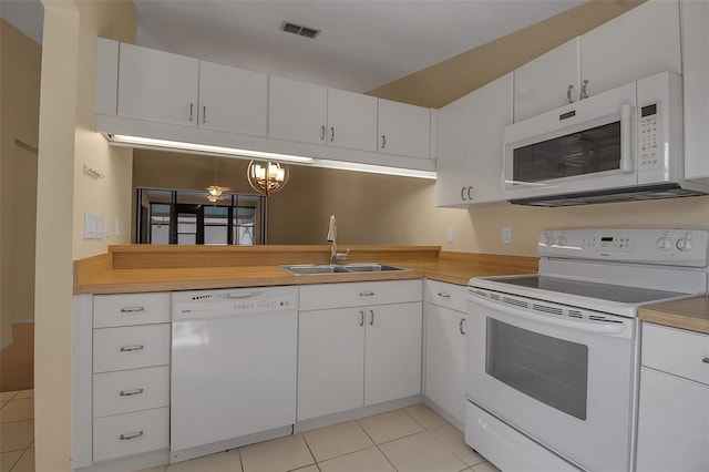 kitchen with white appliances, an inviting chandelier, white cabinets, sink, and light tile patterned floors