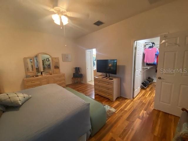 bedroom with a closet, a spacious closet, light wood-type flooring, and ceiling fan