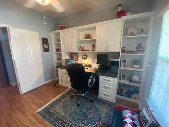 office area with built in desk, ceiling fan, a healthy amount of sunlight, and hardwood / wood-style floors