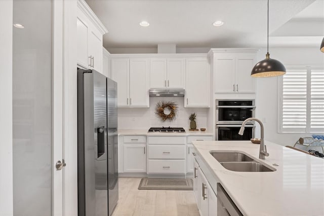 kitchen featuring white cabinets, light stone countertops, stainless steel appliances, sink, and decorative light fixtures