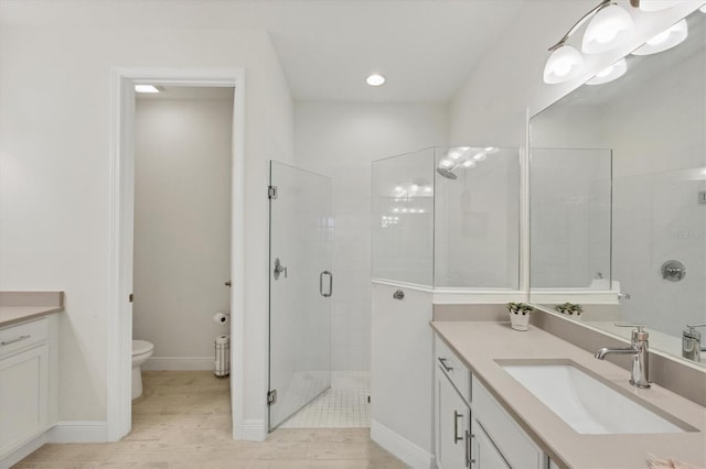 bathroom featuring vanity, a shower with shower door, wood-type flooring, and toilet