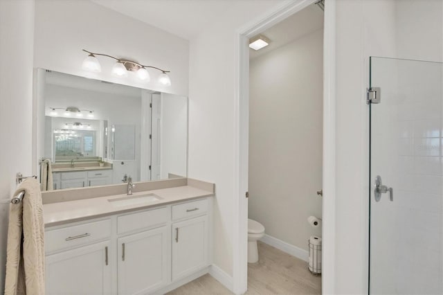 bathroom featuring vanity, toilet, a shower with shower door, and hardwood / wood-style floors