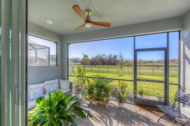 sunroom with ceiling fan and a rural view