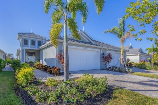 view of front facade featuring an attached garage, decorative driveway, and stucco siding