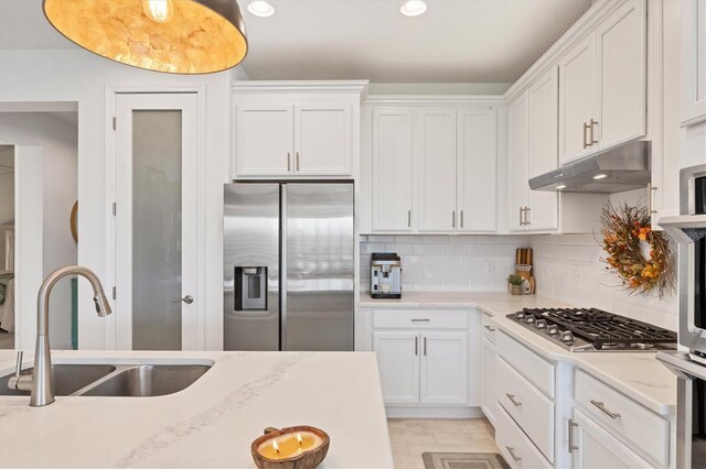 kitchen with stainless steel appliances, white cabinetry, a sink, and under cabinet range hood