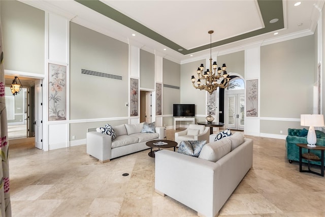 living room featuring crown molding, a notable chandelier, a tray ceiling, and a towering ceiling