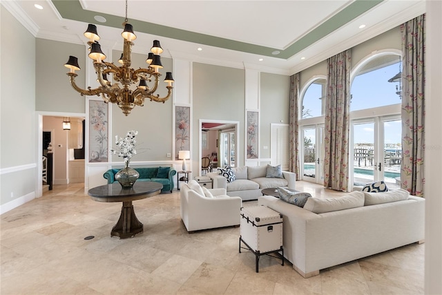 living room with french doors, a notable chandelier, a towering ceiling, and ornamental molding