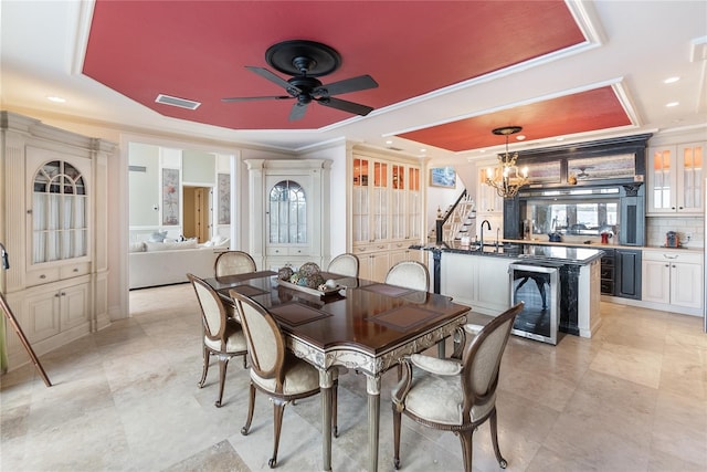 dining room featuring ornamental molding, ceiling fan with notable chandelier, and beverage cooler