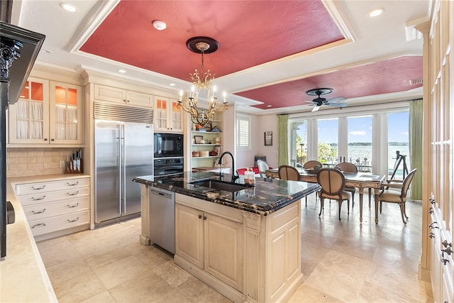 8213 Midnight Pass Rd, Sarasota, FL 34242 - kitchen with decorative backsplash, a center island with sink, a raised ceiling, a sink, and black appliances