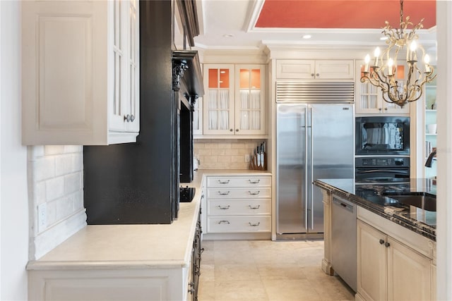 kitchen with black appliances, hanging light fixtures, white cabinets, decorative backsplash, and an inviting chandelier