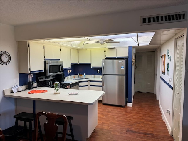 kitchen with appliances with stainless steel finishes, kitchen peninsula, white cabinetry, and sink