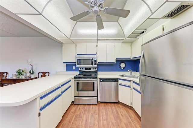 kitchen with light countertops, visible vents, a sink, a peninsula, and appliances with stainless steel finishes