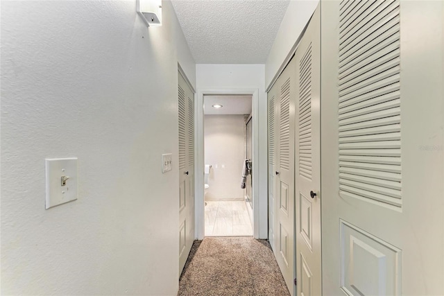 hall featuring carpet floors and a textured ceiling