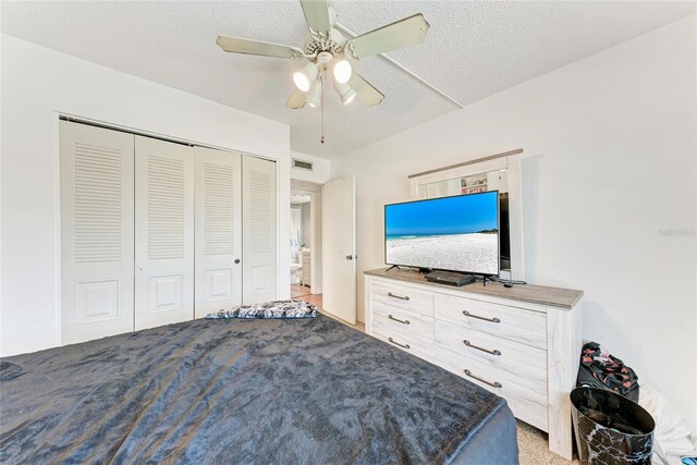 bedroom with visible vents, a ceiling fan, light carpet, a closet, and a textured ceiling