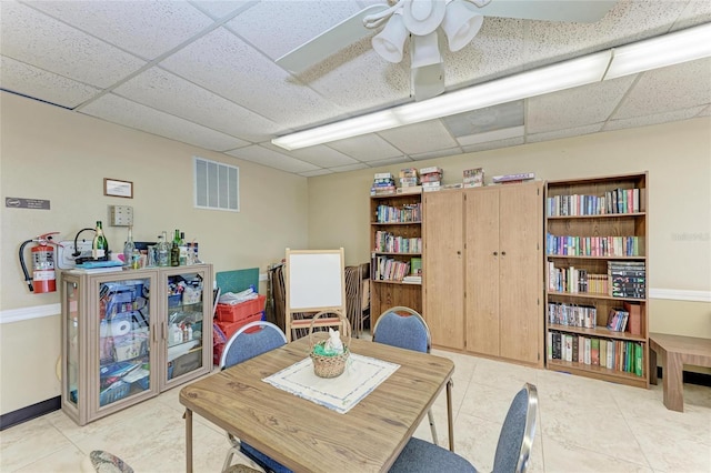 interior space featuring a paneled ceiling, visible vents, tile patterned floors, and ceiling fan