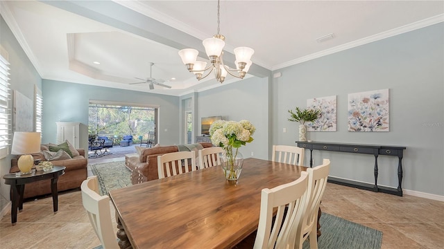 dining space with crown molding, a tray ceiling, and ceiling fan with notable chandelier