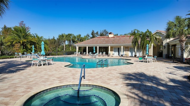 view of pool with a hot tub and a patio area