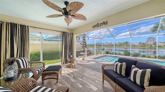 sunroom featuring ceiling fan, a water view, and a pool