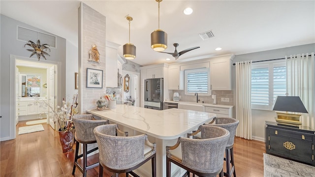 kitchen with kitchen peninsula, white cabinetry, hanging light fixtures, and light hardwood / wood-style flooring