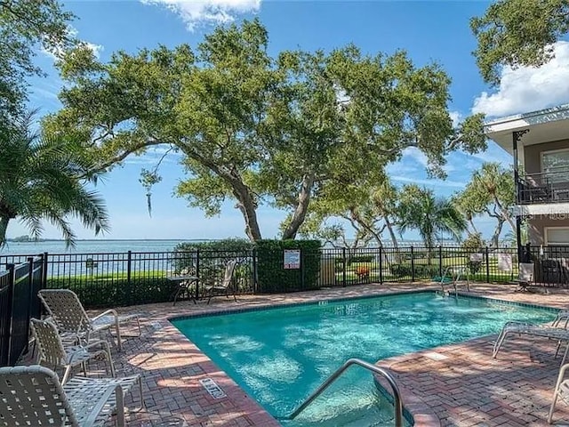 view of pool featuring a water view and a patio area