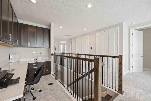 carpeted home office featuring a textured ceiling