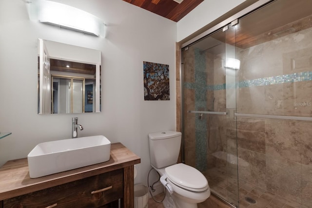 bathroom featuring a shower with door, vanity, and toilet