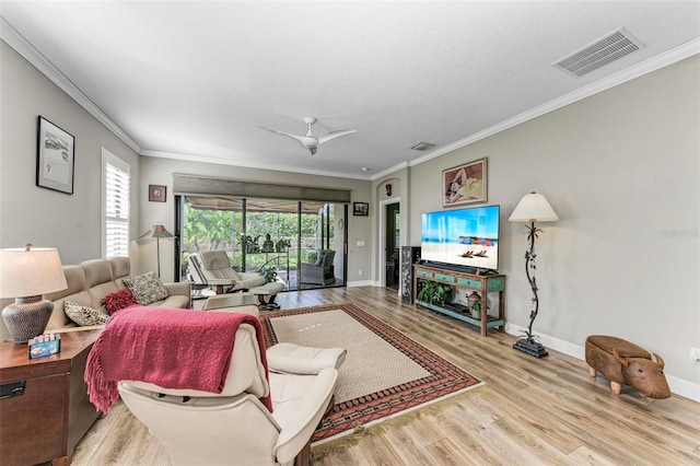 living room with ornamental molding, light wood-type flooring, and ceiling fan