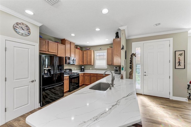 kitchen featuring sink, black appliances, light stone countertops, and light hardwood / wood-style floors