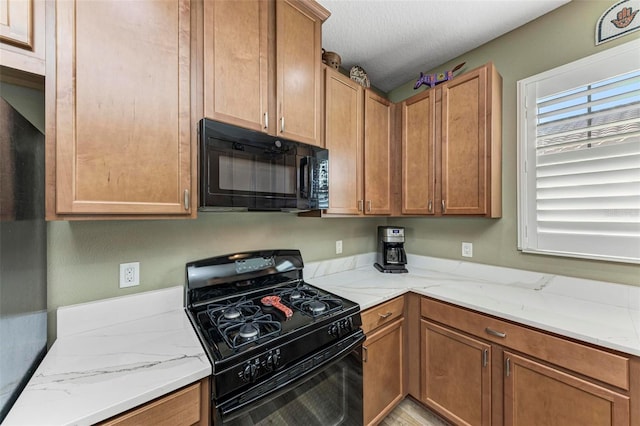 kitchen with black appliances, light stone countertops, and a textured ceiling