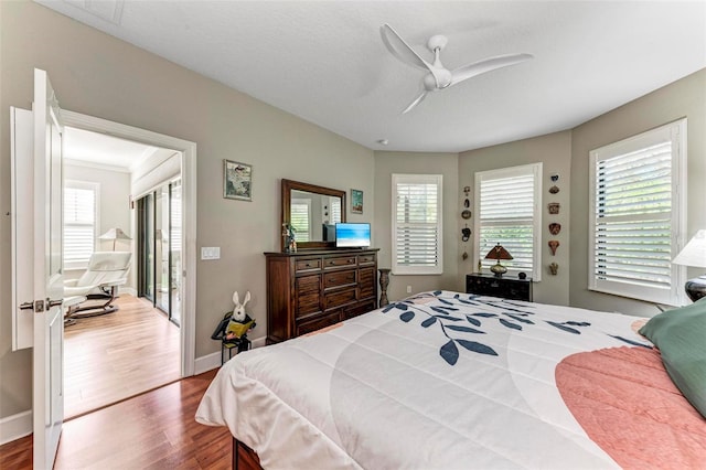 bedroom with ceiling fan, multiple windows, and hardwood / wood-style floors