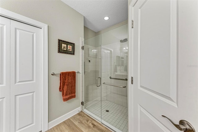 bathroom with a shower with door, hardwood / wood-style flooring, and a textured ceiling