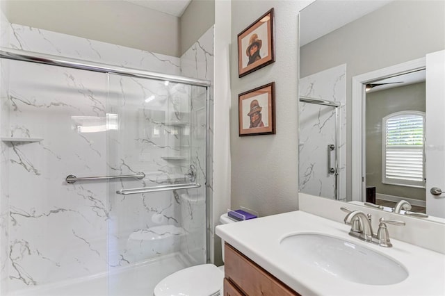 bathroom with a shower with door, vanity, and toilet