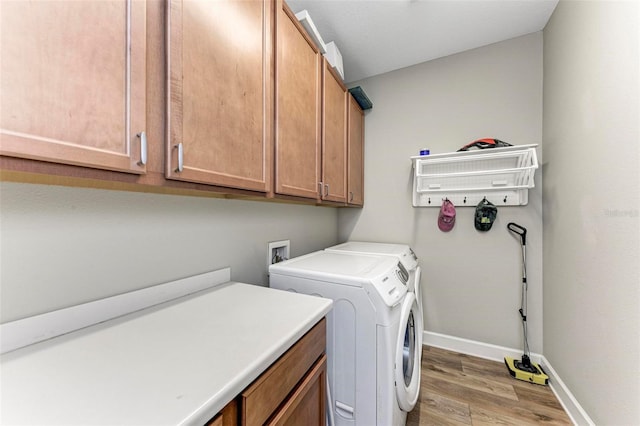 laundry room featuring hardwood / wood-style floors, washing machine and dryer, and cabinets