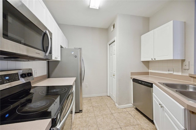 kitchen featuring appliances with stainless steel finishes, sink, white cabinetry, decorative backsplash, and light tile patterned floors