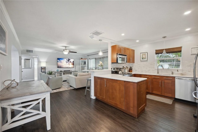 kitchen with dark hardwood / wood-style floors, stainless steel appliances, crown molding, pendant lighting, and tasteful backsplash