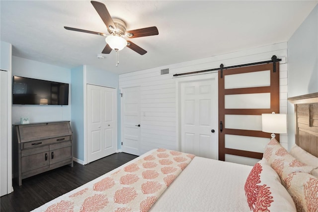 bedroom with a closet, ceiling fan, dark hardwood / wood-style floors, and a barn door