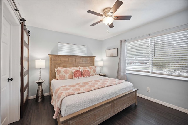 bedroom featuring ceiling fan, dark hardwood / wood-style flooring, and a barn door